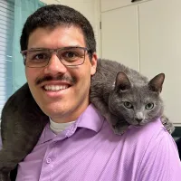 A headshot of James with a cat on his shoulder